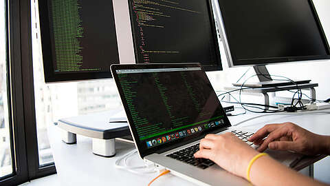 Programmierkenntnisse als wichtige Einstiegskompetenz für IT-Berufe Eine Nahaufnahme eines Computerbildschirms, auf dem Codiersoftware mit leuchtend farbigem Text des Ruby-on-Rails-Codes angezeigt wird, hauptsächlich in Grün, Weiß und Orange auf dunklem Hintergrund.
